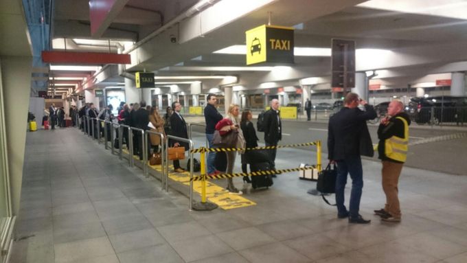 Evakuovaní pasažéři z haly varšavského letiště marně čekají na taxi.
