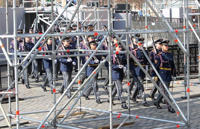 Střídání Hradní stráže mezi rozestavěnými tribunami na Hradčanském náměstí.