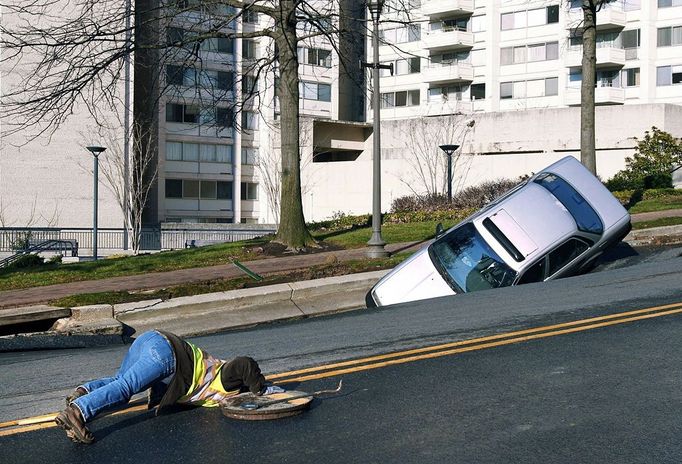 CHEVY CHASE, MD - DECEMBER 3: A utility worker looks underground to examine the scene where a sinkhole caused when a broken water main collapsed part of Friendship Blvd. on December 3, 2010 in Chevy Chase, Maryland. No one was reported injured in the accident. Logan Mock-Bunting