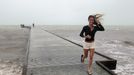 An unidentified woman leaves the pier in high wind and rough surf as Tropical Storm Isaac moves over the island August 26, 2012. Tropical Storm Isaac lashed south Florida with winds and heavy rain on Sunday after battering the Caribbean, disrupting plans for the Republican National Convention in Tampa and threatening to interrupt about half of U.S. offshore oil output. REUTERS/Andrew Innerarity (UNITED STATES - Tags: ENVIRONMENT DISASTER TPX IMAGES OF THE DAY) Published: Srp. 27, 2012, 6:42 dop.