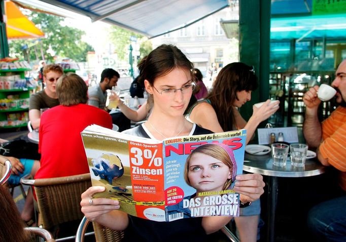 Žena ve vídeňské kavárně čte časopis, na jehož titulní stránce je fotografie Nataschy Kampuschové v televizi. 6. 9. 2006