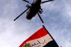 Egypťan zvedá vlajku k nebi, na kterém přelétá vojenská helikoptéra.