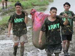 Filipínští vojáci vynášejí v prostěradle oběť sesuvu bahna, který zcela zničil vesnici Guinsaugon.