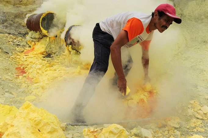 This photo taken on December 25, 2010 shows an Indonesian miner extracting blocks of sulphur with his bare hands from the bottom of the crater of Indonesia's active Kajah Iwen volcano, in the extreme east of Java island. Some 350 sulphur miners eke out a dangerous and exhausting living on the active volcano, carrying hauls of up to 80 kilos of "yellow gold" which will be bought by local factories and used to refine sugar or make matches and medicines. The miners extract the liquid sulphur as it flows out of hot iron pipes. Once in the open air, it cools, crystallises and turns bright yellow. The sulphur is then loaded into wicker baskets at either end of bamboo yokes and carried back over the lip of the crater and down the side of the volcano, a treacherous journey of four kilometres (2.5 miles).