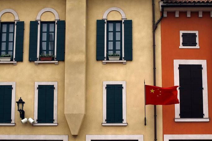 A Chinese national flag flies from buildings resembling those found in an Italian town at the Florentia Village in the district of Wuqing, located on the outskirts of the city of Tianjin June 13, 2012. The shopping center, which covers an area of some 200,000 square meters, was constructed on a former corn field at an estimated cost of US$220 million and copies old Italian-style architecture with Florentine arcades, a grand canal, bridges, and a building that resembles a Roman Coliseum. REUTERS/David Gray (CHINA - Tags: SOCIETY BUSINESS) Published: Čer. 13, 2012, 5:39 odp.