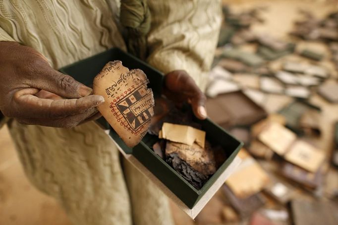 A museum guard displays a burnt ancient manuscript in its box at the Ahmed Baba Institute, or Ahmed Baba Centre for Documentation and Research, in Timbuktu January 31, 2013. The majority of Timbuktu's ancient manuscripts appear to be safe and undamaged after the Saharan city's 10-month occupation by Islamist rebel fighters, experts said on Wednesday, rejecting some media reports of their widespread destruction. REUTERS/Benoit Tessier (MALI - Tags: POLITICS CIVIL UNREST CONFLICT SOCIETY) Published: Led. 31, 2013, 3:25 odp.