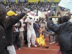 Rwandští demonstranti pálí francouzskou vlajku při protestu proti požadavku Francie postavit prezidenta Paula Kagameho před soud za účast na genocidě.