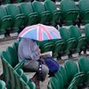 A spectator shelters under an umbrella at the Wimbledon Tenn