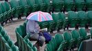 A spectator shelters under an umbrella at the Wimbledon Tennis Championships, in London June 27, 2013. REUTERS/Toby Melville (BRITAIN - Tags: SPORT TENNIS)