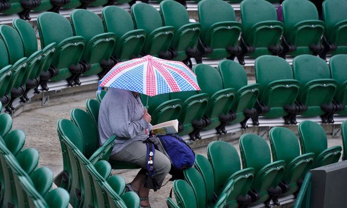 A spectator shelters under an umbrella at the Wimbledon Tennis Championships, in London June 27, 2013. REUTERS/Toby Melville (BRITAIN - Tags: SPORT TENNIS)