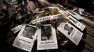 Flowers with a banner reading &quot;World Cup of deaths&quot; draped across them are placed on the ground next to pictures of workers who died during construction of Worl