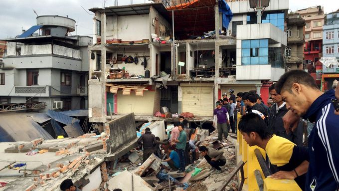 Lidé prozkoumávají ruiny zřícených budov po silném zemětřesení v Káthmándú.
