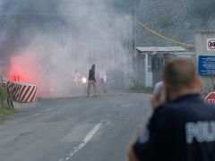 Kosovský policista z povzdálí sleduje řádění maskované skupiny na přechodu Jarinje.