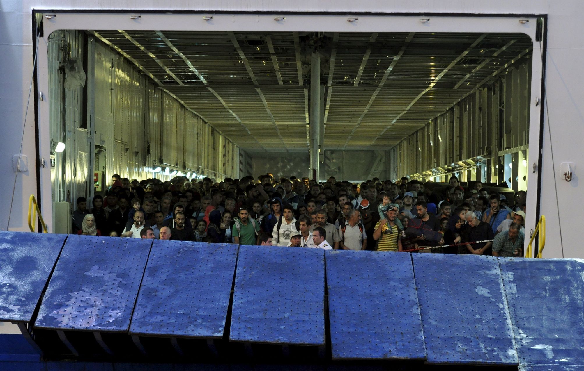 Syrští uprchlíci se chystají vyjít na pevninu v řeckém přístavu Pireus.