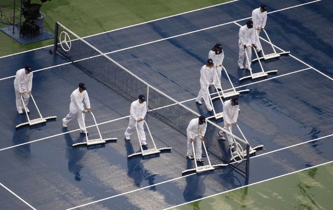 Zřízenci vysušují centrkurt ve Flushing Meadows.