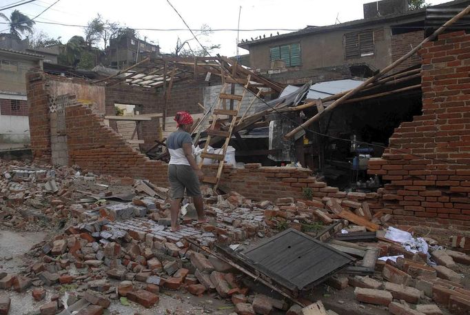 A woman stands outside her house, damaged by Hurricane Sandy, in Santiago de Cuba October 25, 2012. Strengthening rapidly after tearing into Jamaica and crossing the warm Caribbean Sea, Sandy hit southeastern Cuba early on Thursday with 105-mph winds that cut power and blew over trees across the city of Santiago de Cuba. Reports from the city of 500,000 people, about 470 miles (750 km) southeast of Havana spoke of significant damage, with many homes damaged or destroyed. REUTERS/Miguel Rubiera/Cuban Government National Information Agency - AIN/Handout (CUBA - Tags: ENVIRONMENT DISASTER TPX IMAGES OF THE DAY) FOR EDITORIAL USE ONLY. NOT FOR SALE FOR MARKETING OR ADVERTISING CAMPAIGNS. THIS IMAGE HAS BEEN SUPPLIED BY A THIRD PARTY. IT IS DISTRIBUTED, EXACTLY AS RECEIVED BY REUTERS, AS A SERVICE TO CLIENTS Published: Říj. 25, 2012, 6:23 odp.