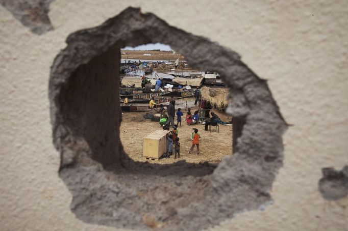 A fish market is seen through a hole in the wall in Konna, Mali, January 27, 2013. REUTERS/Joe Penney (MALI - Tags: POLITICS MILITARY CONFLICT SOCIETY) Published: Led. 27, 2013, 4:46 odp.