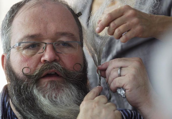 German hairdresser Elmar Weisser, 48, is reflected in a mirror in his hotel room as he starts shaping his beard as a stork, with help from his wife, to compete in the 2012 European Beard and Moustache Championships in Wittersdorf near Mulhouse, Eastern France, September 22, 2012. Weisser, who won the World Beard and Moustache Championship in 2011, ranked second in the freestyle category of the European championships on Saturday. Picture taken September 22, 2012. REUTERS/Vincent Kessler (FRANCE - Tags: SOCIETY) Published: Zář. 23, 2012, 12:13 odp.