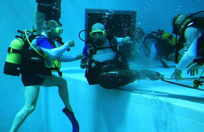 French athlete Philippe Croizon (C), whose arms and legs were amputated after an electric shock accident in March 1994, swims next to unidentified divers in a 33 metre (36 yard) deep pool, the world's deepest pool built to train professional divers, at Nemo33 diving centre in Brussels January 10, 2013. Croizon, who swam with adapted prostheses that had fins attached, broke a world record and became the first disabled person to dive to 33 metres, according to the organisers. REUTERS/Yves Herman (BELGIUM - Tags: SOCIETY SPORT DIVING) Published: Led. 10, 2013, 4:32 odp.