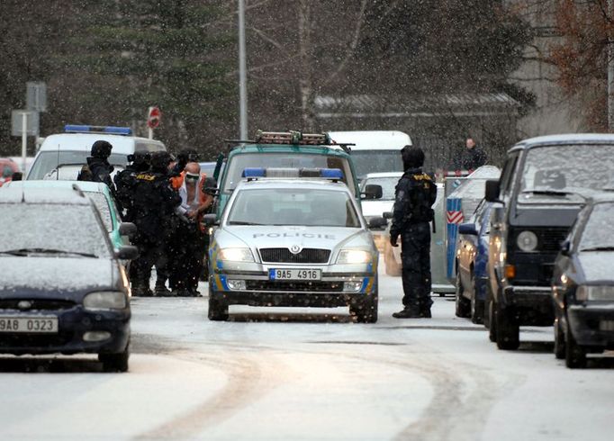 Policie vede zadrženého lupiče k autu