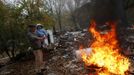 Justo Gabarri tries to keep his grandson Joel warm next to a bonfire as a bulldozer demolishes a home in the background in the Spanish gypsy settlement of Puerta de Hierro, in the outskirts of Madrid November 20, 2012. Fifty-four families have been living in Puerta de Hierro, on the banks of the Manzanares river for over 50 years. Since the summer of 2010, the community has been subject to evictions on the grounds that the dwellings are illegal. Families, whose homes have been demolished, move in with relatives whose houses still remain while the debris keeps piling up around them as more demolitions take place. Justo Gabarri's home was the second of two houses that got demolished Tuesday. REUTERS/Susana Vera (SPAIN - Tags: CIVIL UNREST BUSINESS CONSTRUCTION) Published: Lis. 20, 2012, 4:51 odp.