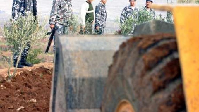 Buldozer vyhrabává těla z hromadného hrobu objeveného v Libanonu na místě, kde sídlila syrská tajná služba.