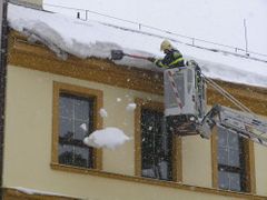 Hasiči ostraňují sníh ze střechy.
