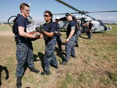 Američané nakládají do helikoptéry balíky vody.