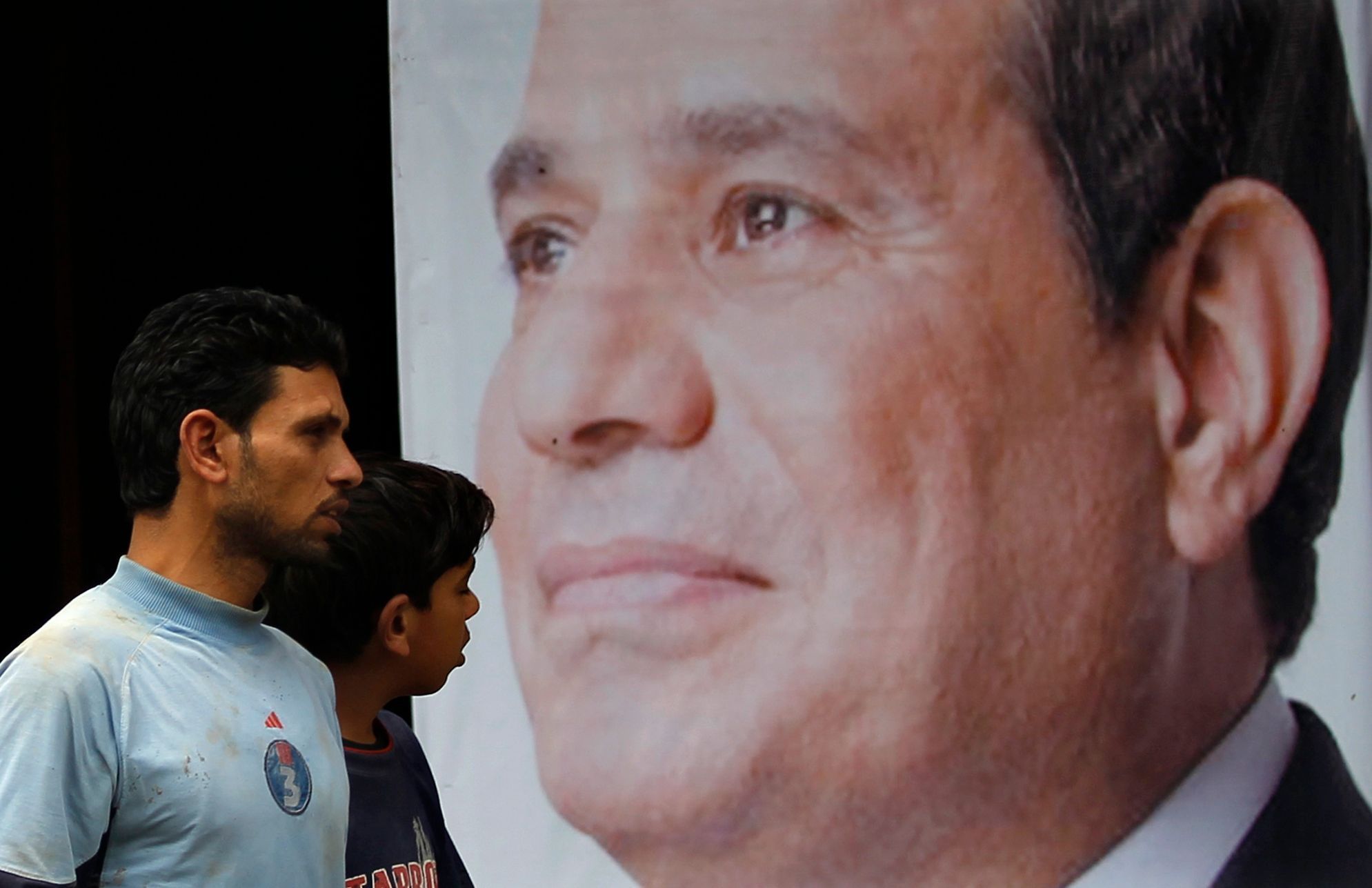 People walk past a poster of presidential candidate Abdel Fattah al-Sisi at one of his campaign headquarters in Cairo