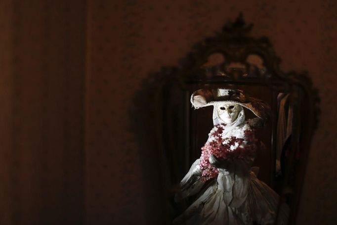 Nadia, wife of Marco Dilauro, is reflected in a mirror as she wears one of his creations, an elaborate costume for the Venice Carnival January 25, 2013. Marco Dilauro, 43, is a tax collector by day, but his real passion is making masks and costumes for the carnival. A resident of Como, northern Italy, he chooses fabrics, ribbons, lace and costume jewellery to make the period costumes after doing extensive research, and wears them at Carnival, which ends on the day before Ash Wednesday. Picture taken January 25, 2013. REUTERS/Alessandro Bianchi (ITALY - Tags: SOCIETY) Published: Led. 27, 2013, 11:40 odp.