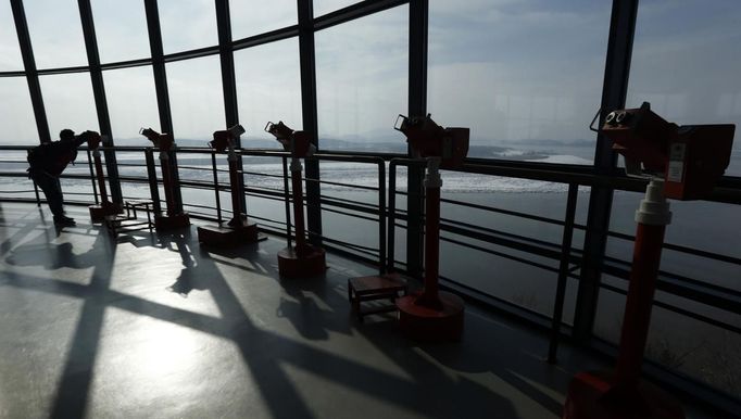 A Japanese tourist looks at the village of Gijungdong, North Korea, from a South Korean observation post, just south of the demilitarized zone separating the two Koreas, in Paju, north of Seoul, February 6, 2013. New York under missile attack is a remote dream for impoverished North Korea, yet that is precisely what the latest propaganda video from the isolated state shows as it readies a third nuclear test. North Korea has trailed plans to carry out a third nuclear test, which experts believe is imminent. REUTERS/Lee Jae-Won (SOUTH KOREA - Tags: MILITARY POLITICS ENERGY) Published: Úno. 6, 2013, 8:09 dop.