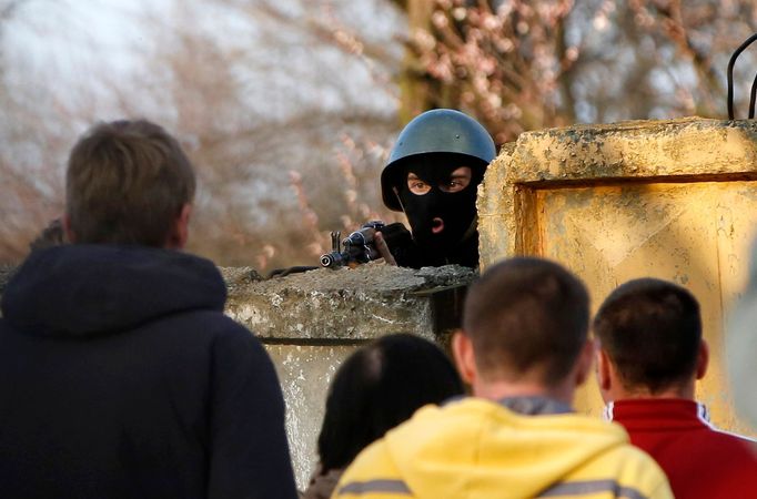 An Ukrainian soldier aims his rifle at pro-Russia protesters gathered in front of a Ukrainian airbase in Kramatorsk, in eastern Ukraine April 15, 2014.