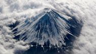 Letecký snímek. Hora Fuji (3 776 m) je nejvyšší horou Japonska. Nachází se na hranici mezi prefekturami Šizuoka a Jamanaši asi 100 km na západ od Tokia. Na tomto snímku je pokryta sněhem a zahalena do oblačné peřiny.