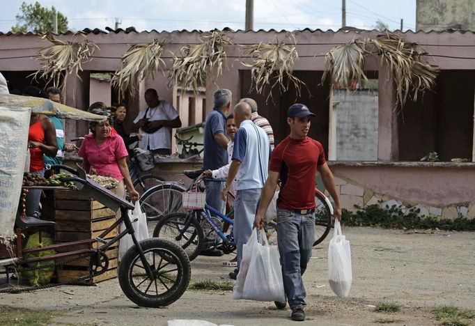 Luis Salgado (R), nicknamed Chucho, carries goods he bought near their home in the village of Sagua La Grande in central Cuba, March 10, 2013. Chucho was granted a U.S. visa based on his father's status as legal resident in Texas, and he was reunited in Miami with his father, Jesus Salgado, who had escaped Cuba on a frail boat ten years earlier. The Salgados are among many Cubans taking advantage of Cuba's new travel policy in place since last January, which allows citizens to leave the country with just a passport and no need for much-hated exit visas required since 1961. Picture taken March 10, 2013. REUTERS/Desmond Boylan (CUBA - Tags: POLITICS SOCIETY) Published: Dub. 11, 2013, 2:02 odp.