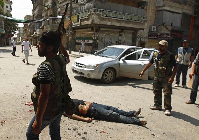 ATTENTION EDITORS - VISUAL COVERAGE OF SCENE OF DEATH OR INJURY A Free Syrian Army member walks past the body of what they say is a member of Syrian President Bashar al-Assad's shabiha militia at Aleppo's disctrict of al-Sukkari July 29, 2012. REUTERS/Zohra Bensemra (SYRIA - Tags: POLITICS CONFLICT CIVIL UNREST MILITARY TPX IMAGES OF THE DAY) TEMPLATE OUT Published: Čec. 29, 2012, 8:19 odp.