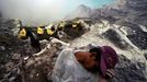 Indonesia - Living Dangerously A miners rests on a rock, exhausted from the climb up from the crater carrying between 80 and 110kg of sulfur from the sulfur mine on the I