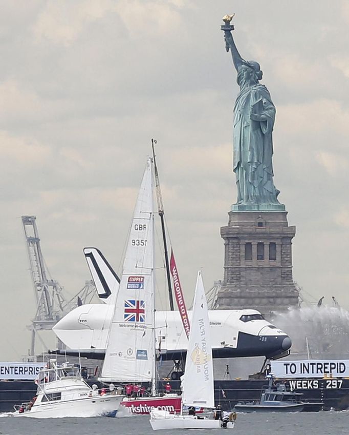 The Space Shuttle Enterprise, passes the Statue of Liberty as it rides on a barge in New York harbor, June 6, 2012. The Space Shuttle Enterprise was being moved up the Hudson River to be placed at the Intrepid Sea, Air and Space Museum. REUTERS/Brendan McDermid (UNITED STATES - Tags: SCIENCE TECHNOLOGY TRANSPORT) Published: Čer. 6, 2012, 5:13 odp.