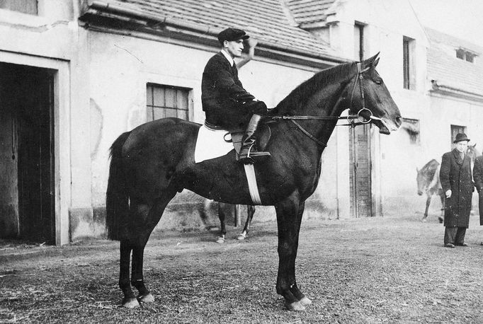 Josef Šach na koni Vardar před chuchelskými stájemi. Jedná se o nejstarší chuchelské stáje, které stojí dodnes. Šach vyhrál mezi lety 1949 a 1975 pět ročníků Čs. derby.