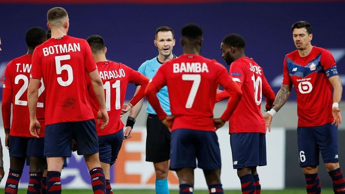 Slovenský arbitr Ivan Kružliak čelí zlobě naštvaného hroznu fotbalistů Lille, proti nimž odpískal v závěru utkání play off Evropské ligy nesmyslnou penaltu.