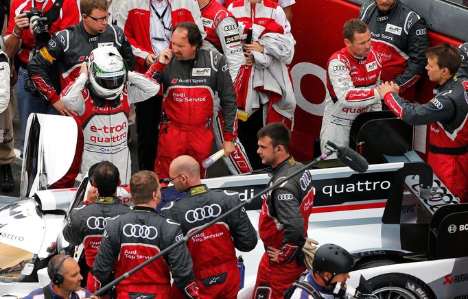 Driver of Audi R18 E-Tron Quattro Allan McNish (L) of Britain adjusts his helmet as driver number 2 Tom Kristensen (R) of Denmark speaks with a mechanic, just before the