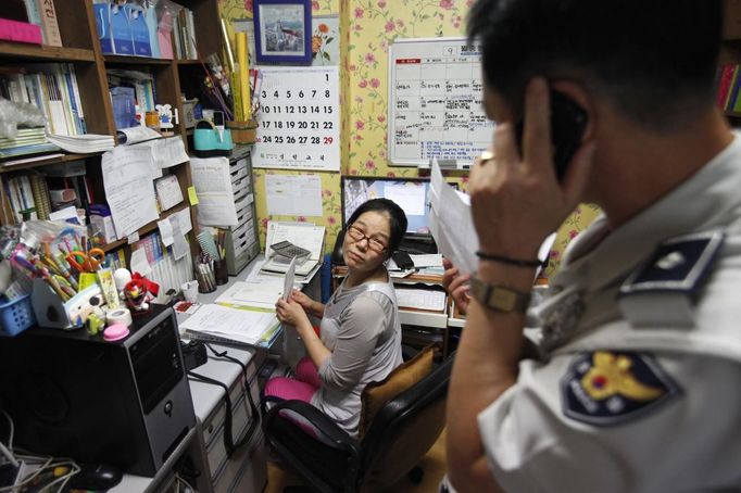 A policeman (R) talks on a phone as preacher Jeong Young-ran looks on after a mother abandoned her baby at a "baby box" at Joosarang church in Seoul September 18, 2012. A South Korean pastor who runs a "baby box" where mothers can leave unwanted infants has seen a sharp increase in the number of newborns being left there because, the pastor says, of a new law aimed protecting the rights of children. South Korea is trying to shed a reputation of being a source of babies for adoption by people abroad. It is encouraging domestic adoption and tightening up the process of a child's transfer from birth mother to adoptive parents. Picture taken September 18, 2012. REUTERS/Kim Hong-Ji (SOUTH KOREA - Tags: SOCIETY) Published: Říj. 7, 2012, 6:48 dop.