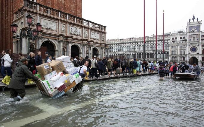 A worker transports materials in St. Mark Square during a period of seasonal high water in Venice October 27, 2012. The water level in the canal city rose to 127 cm (50 inches) above the normal level, according to the monitoring institute. REUTERS/Manuel Silvestri (ITALY - Tags: ENVIRONMENT SOCIETY TRAVEL) Published: Říj. 27, 2012, 12:25 odp.