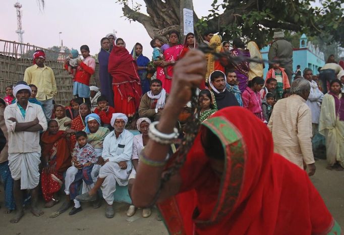 People watch a devotee, believed to be possessed by evil spirits, dance while holding an iron chain in a state of trance at Guru Deoji Maharaj temple during a ghost fair at Malajpur village in Betul district in the central Indian state of Madhya Pradesh January 27, 2013. People from across India come to this fair to be exorcised of �evil spirits�. They are usually brought by relatives and they are most often women. The exorcism involves running around the temple courtyard to make the 'ghost' weak then being beaten by a priest with a broom. Picture taken January 27, 2013. REUTERS/Danish Siddiqui (INDIA - Tags: SOCIETY RELIGION TPX IMAGES OF THE DAY) ATTENTION EDITORS: PICTURE 7 OF 24 FOR PACKAGE 'INDIAN GHOSTBUSTERS' SEARCH 'INDIA GHOST' FOR ALL IMAGES Published: Úno. 5, 2013, 5:09 dop.