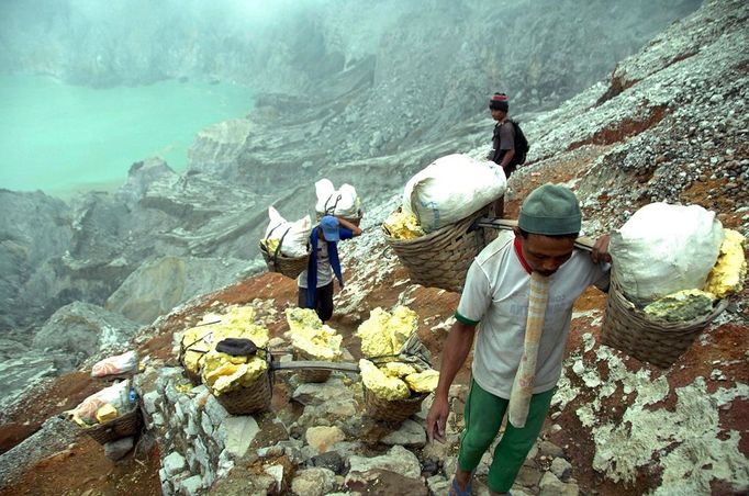 To go with story Indonesia-volcano-mine by Jerome Rivet A picture taken on April 26, 2010 shows Indonesian sulphur miners carrying blocks of sulphur from the caldera (behind) down the Kawah Ijen, or Ijen crater, in Bondowoso in East Java. Indonesian porters at Kawah Ijen, a famous tourist spot in Indonesia's East Java, mine and carry at least 70 kg-worth of sulphur blocks on their shoulders through the suffocating clouds of toxic gases each day receiving just 70,000 to 80,000 rupiah (7 - 8 US dollars) for their labour.