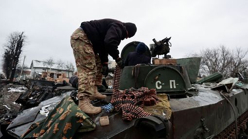 Obyvatelé ukrajinské Buči vyndávají z rozbitého ruského tanku náboje.