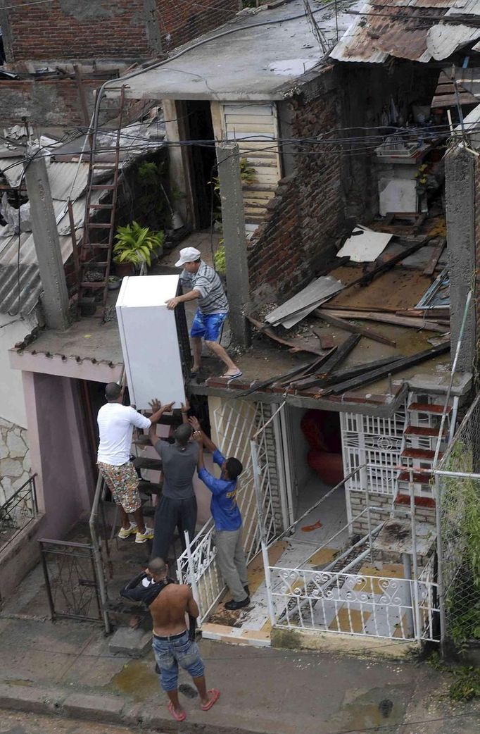 A resident (top) salvages a refrigerator from his damaged house, with the help of other men, after Hurricane Sandy hit Santiago de Cuba October 25, 2012. Strengthening rapidly after tearing into Jamaica and crossing the warm Caribbean Sea, Sandy hit southeastern Cuba early on Thursday with 105-mph winds that cut power and blew over trees across the city of Santiago de Cuba. Reports from the city of 500,000 people, about 470 miles (750 km) southeast of Havana spoke of significant damage, with many homes damaged or destroyed. REUTERS/Miguel Rubiera/Cuban Government National Information Agency-AIN/Handout (CUBA - Tags: DISASTER ENVIRONMENT TPX IMAGES OF THE DAY) FOR EDITORIAL USE ONLY. NOT FOR SALE FOR MARKETING OR ADVERTISING CAMPAIGNS. THIS IMAGE HAS BEEN SUPPLIED BY A THIRD PARTY. IT IS DISTRIBUTED, EXACTLY AS RECEIVED BY REUTERS, AS A SERVICE TO CLIENTS Published: Říj. 25, 2012, 9:59 odp.