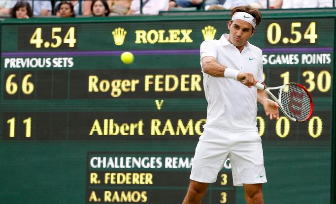 Švýcarský tenista Roger Federer odráží míček během utkání se Španělem Albertem Ramosem v 1. kole Wimbledonu 2012.