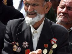 Váleční veteráni v tvídových sakách vyšňořených sovětskými medailemi působili na oslnivém slunci křehce