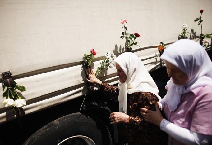 Bosnian women touches one of the three trucks carrying 520 coffins of newly identified victims of the 1995 Srebrenica massacre in front of the presidential building in Sarajevo July 9, 2012. The bodies of the recently identified victims will be transported to the memorial centre in Potocari where they will be buried on July 11 marking the 17th anniversary of the massacre in which Bosnian Serb forces commanded by Ratko Mladic killed up to 8,000 Muslim men and boys and buried them in mass graves. REUTERS/Dado Ruvic (BOSNIA AND HERZEGOVINA - Tags: ANNIVERSARY CIVIL UNREST POLITICS) Published: Čec. 9, 2012, 11:02 dop.