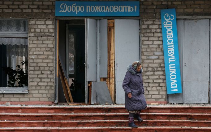 Žena prochází kolem školy ve městě Horlivka, kterou zasáhla střela. Na nápisu na škole se píše "Vítejte".